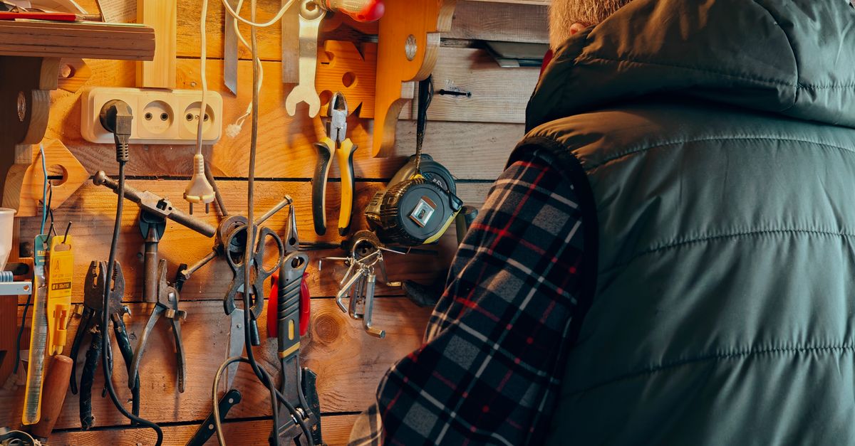 A person working in a wood-paneled workshop surrounded by tools.